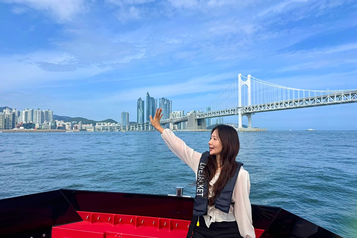 Guest standing on the boat with Gwangan Bridge behind