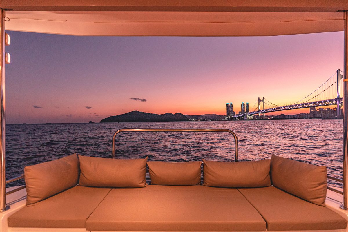 Lounge sofa on the BALI yacht with Gwangan Bridge at sunset in view