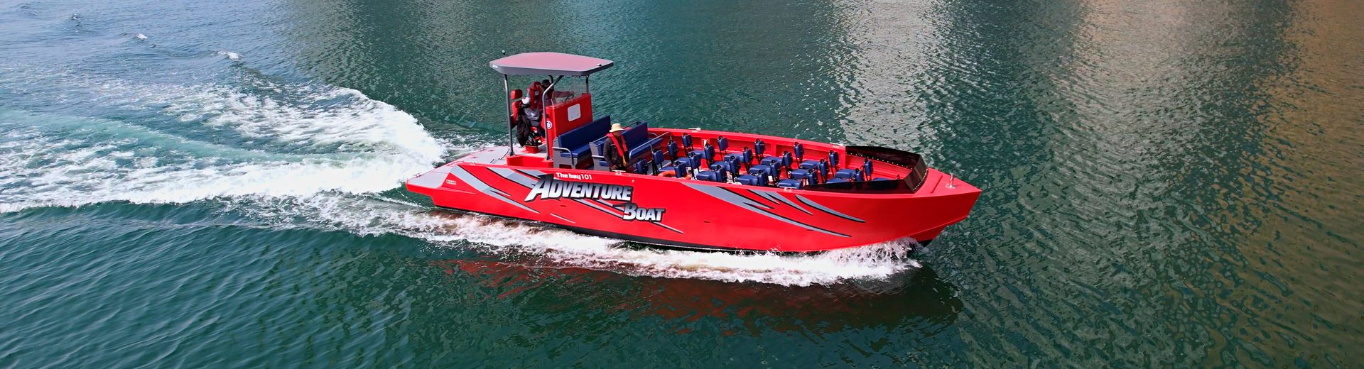 Red adventure boat slicing through the waves