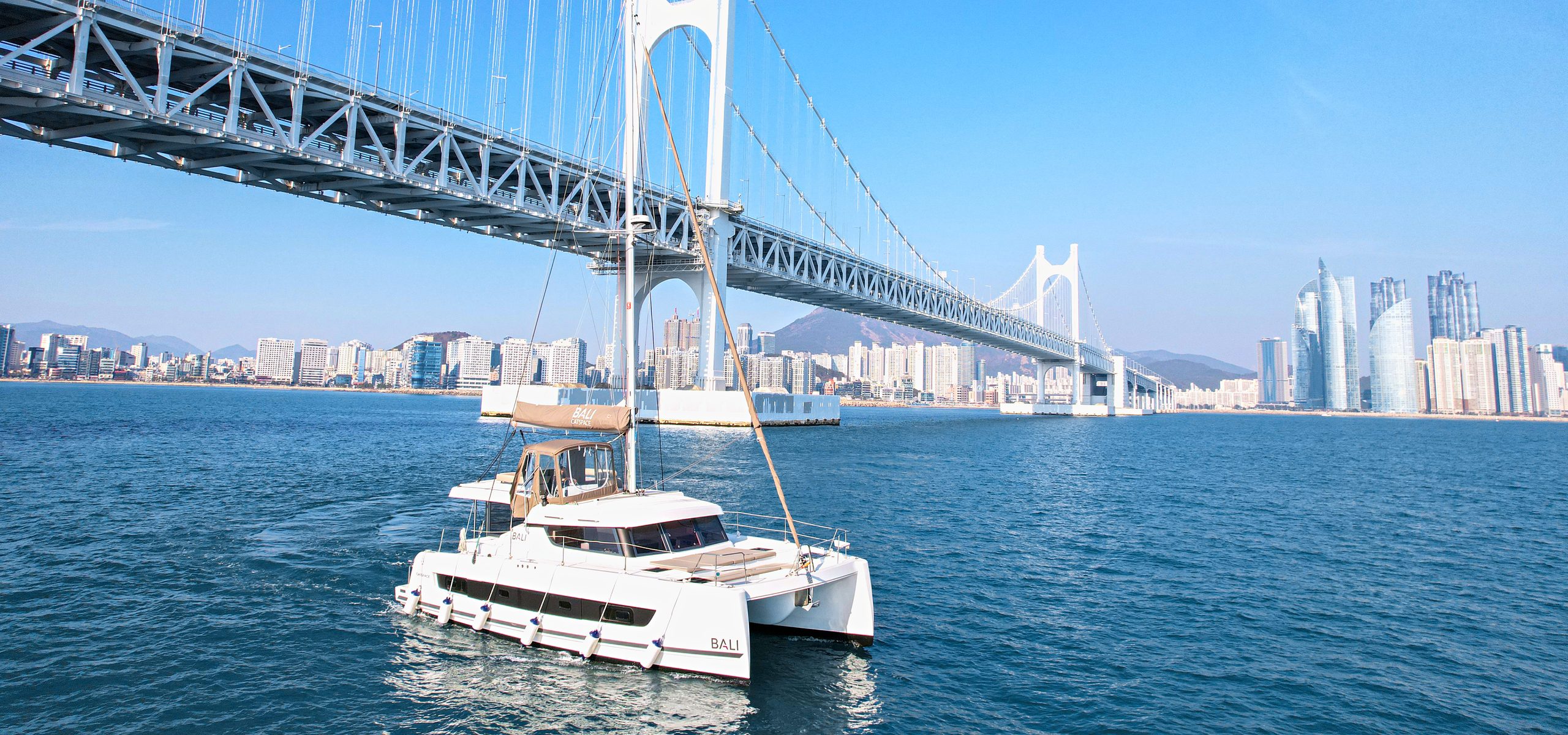 The Bay 101 yacht sailing past Gwangan Bridge on a clear day