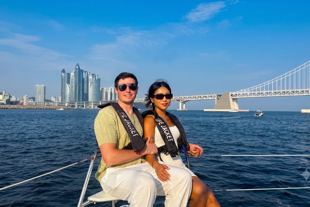 Couple sitting on the yacht with Marine City and Gwangan Bridge behind